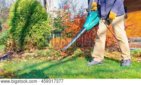 Lawn Care Work. Cleaning The Lawn From Foliage With A Blower In The Autumn Season. A Gardener Remove