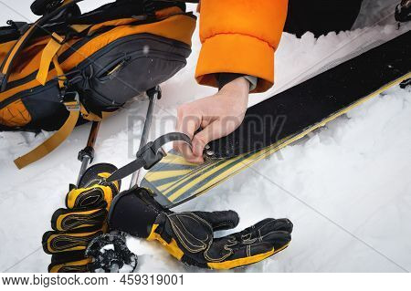 Close-up Of A Mans Hand, Adjusting The Skis Against The Background Of Snow And Things, Putting On Th