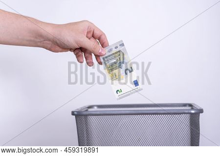The Hand Throws Five Euros In The Trash. The Concept Of The Devaluation Of The Euro.