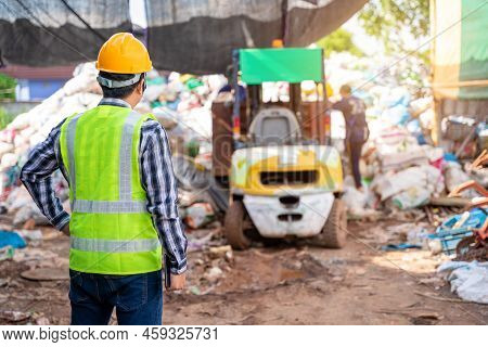 Asian Foreman Stand And Watch The Workers At Recycle Waste Factory With A Forklift On The Background
