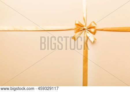 Top View Of Gold Ribbon Rolled And Yellowbow Isolated On Colored Background. Flat Lay With Copy Spac