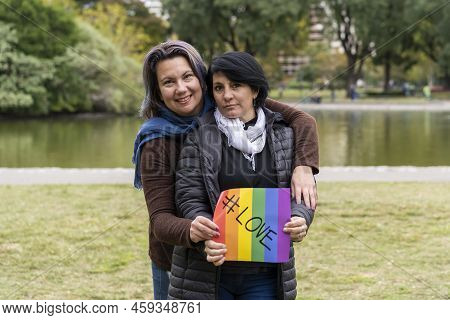 Love. Cheerful Queer Couple Holding A Message Supporting The Lgbt Community