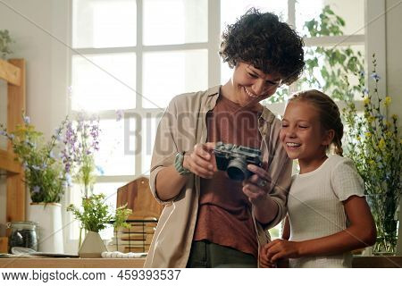 Cute Cheerful Girl Looking At Her New Photos In Photocamera Held By Her Mother