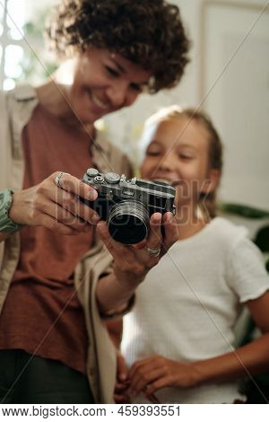 Hands Of Young Woman Holding Photocamera And Showing Photos To Girl