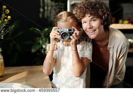 Young Cheerful Woman Looking At Camera While Standing Next To Her Daughter