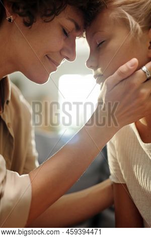 Happy Young Woman Touching Her Cute Daughter By Hand And Forehead