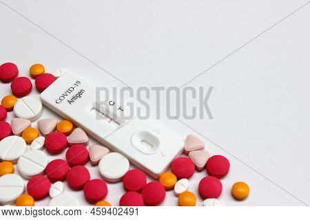 Positive Test Result Of Covid-19 Antigen Test Kit And Drug Tablets On The White Background