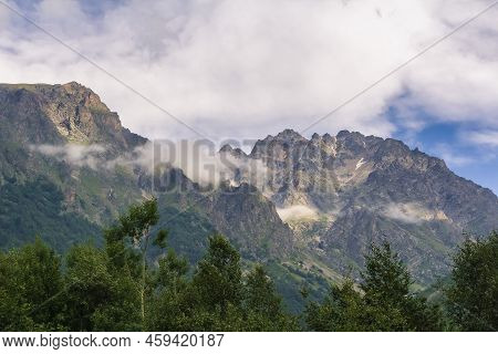 View Of Huge Mountains With Waterfalls And Beautiful Clouds In North Ossetia.