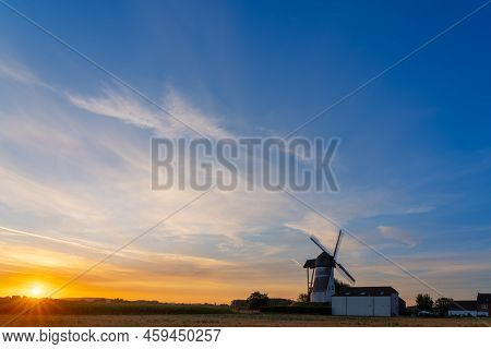 Early In The Morning There Is A Beautiful Windmill Whit The Sun Rising In The Sky