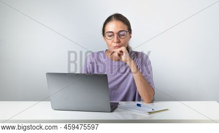 Brooding Girl At A Laptop With A Notebook And A Pen - Remote Learning, Online Education. High Qualit