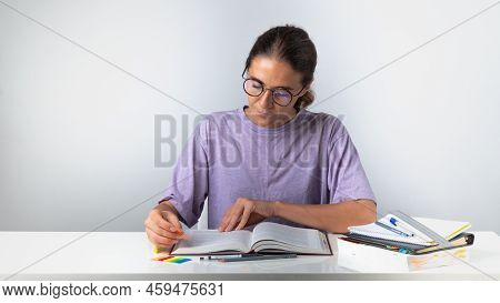 The Student Makes Notes And Bookmarks In The Textbook. High Quality Photo