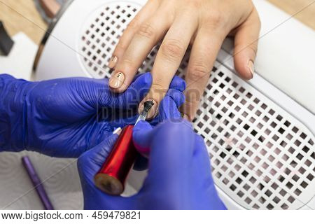 The Manicurist Applies A Topcoat To The Finished Hybrid Nails With A Brush.
