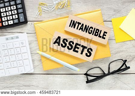Intangible Assets Text On Wood Block On Yellow Notepad
