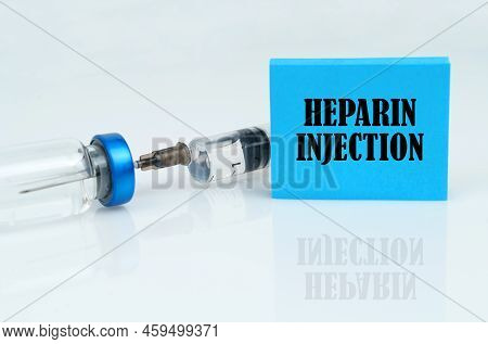 Medical Concept. On A White Reflective Surface There Is A Syringe With An Ampoule And A Blue Plate W