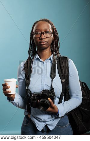 Young Photography Entusiast Having Photo Equipment While Enjoying Beverage On Blue Background. Serio