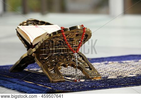 Rehal With Open Quran And Misbaha On Muslim Prayer Rug Indoors