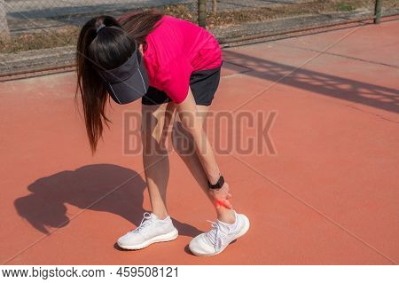 Runner Woman Touching Her Ankle While Suffering From Ankle Pain. Ankle Pain May Be Caused By An Inju