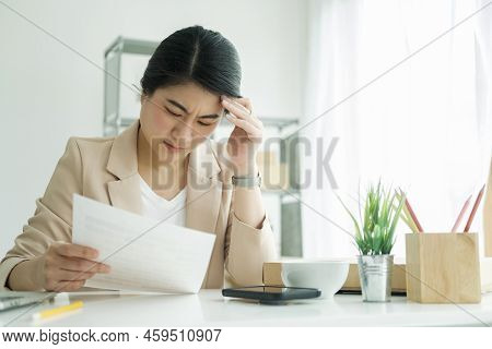 An Unhappy Young Asian Female Freelan Standing Reading In Report On Paper In Online Clothing Store.w