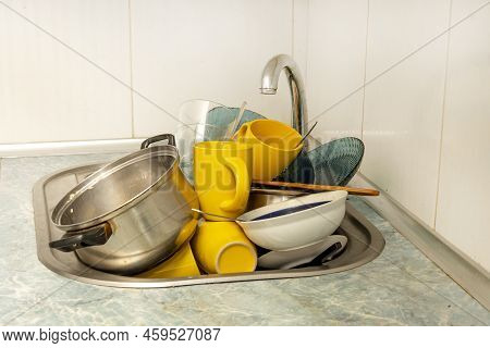 Dirty And Unwashed Dishes Are Stacked In The Kitchen Sink. Unwashed Cups, Plates, Pots, Forks And Sp