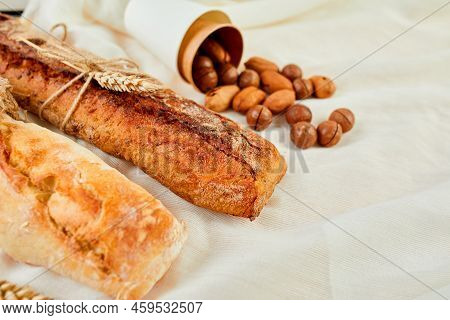 Top View Of Two Baguettebread And Nuts On A Textile Surface.