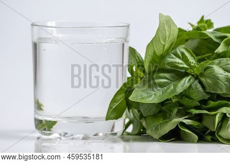 Chlorophyll Extract And Basil Is Poured In Pure Water In Glass Against A White Background And Green 
