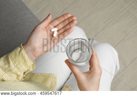 Calcium Supplement. Woman Holding Glass Of Water And Pills Indoors, Top View