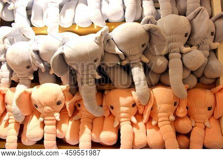 Stuffed Animals Arranged In A Shelf For Sale. Grey And Peach Colored Elephants Stuffed In A Shelf.