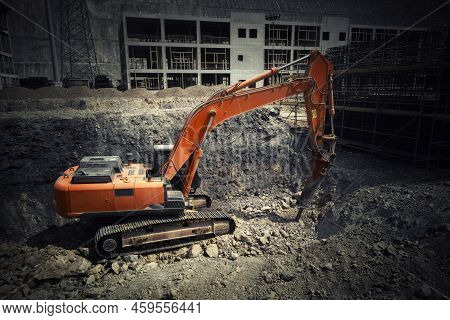 Orange Colored Excavator With Hydraulic Hammer Digs Soil Inside Of Foundation Pit At Construction Si