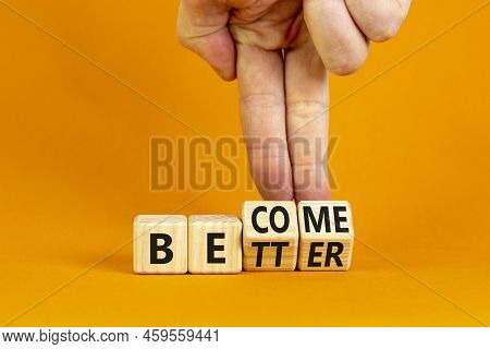 Become Better Symbol. Businessman Turns Wooden Cubes And Changes The Concept Word Better To Become. 