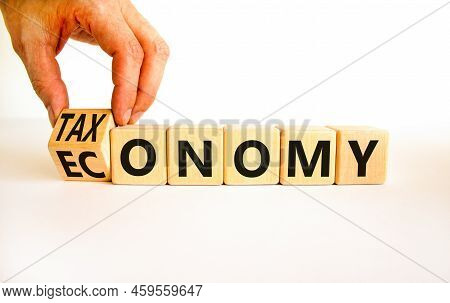 Taxonomy Or Economy Symbol. Businessman Turns Wooden Cubes And Changes The Concept Word Economy To T