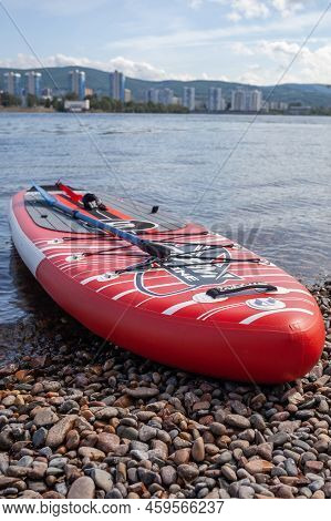 12.07.2022 Krasnoyarsk, Russia. Red Sup Board On The River Bank. Paddle Board On The Lake Shore. Sup