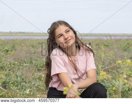 A Beautiful Girl Dreamily Looks Into The Distance Resting In Nature. Portrait Of A Smiling Teenage G