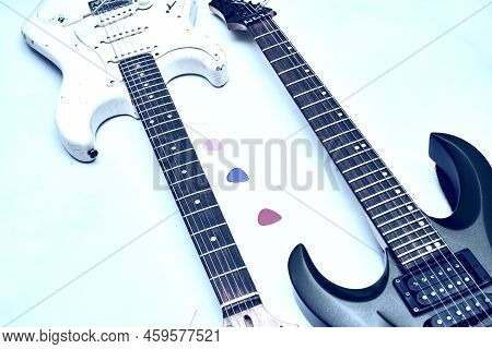 Two Guitar, Neck Fretboard Mediators Plectrum On A Pale Blue.black, White