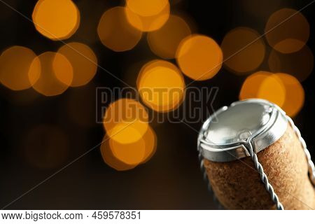 Sparkling Wine Cork With Muselet Cap Against Blurred Festive Lights, Closeup. Space For Text