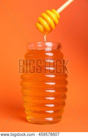 Jar Of Organic Honey And Dipper On Orange Background