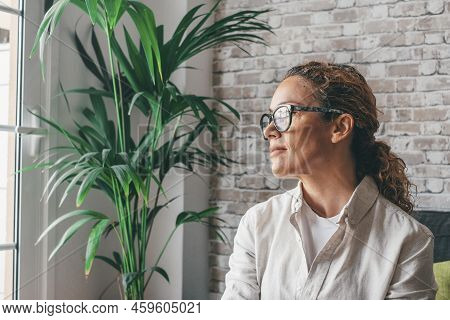 Thoughtful Relaxed Young Woman In Casual Clothes Sitting On Couch In Cozy Modern Living Room Looking