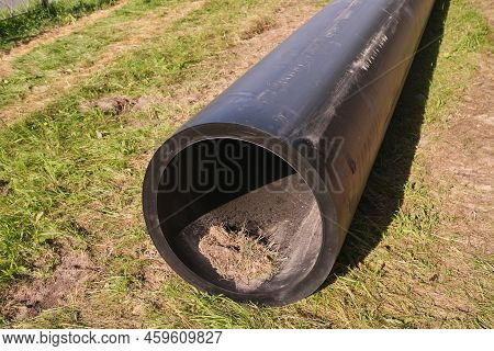 Front View On Long Black Water Hdpe Pipe With Blue Stripe At Construction Site. Large Black Plastic 