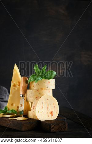 Stack Of Cheese With Tomatoes And Seasoning And Swiss Cheese On With Basil And Knife On Serving Boar