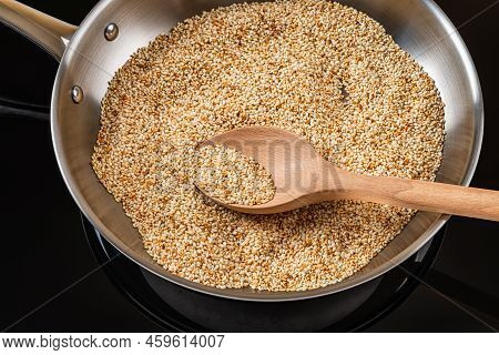 Sesame Seeds Toasting In A Stainless Steel Frying Pan. Roasting White Til In A Skillet. Organic Benn