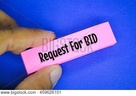 Hand Holding A Pink Paper With The Word Request For Bid