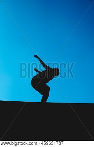 Silhouette Of A Man Doing Warm-ups In The Park. Man Practicing Exercise With The Sky In The Backgrou