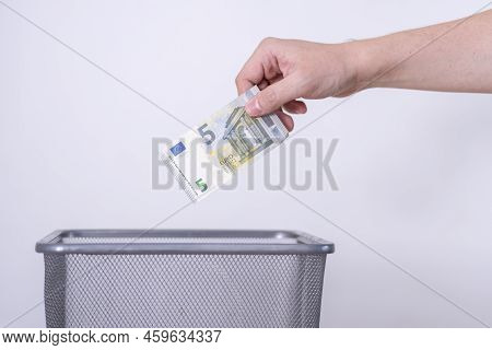 The Hand Throws Five Euros In The Trash. The Concept Of The Devaluation Of The Euro.
