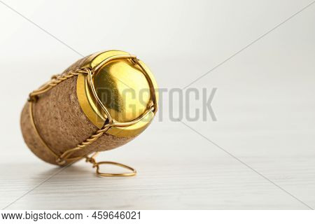 Cork Of Sparkling Wine And Muselet Cap On White Wooden Table, Closeup. Space For Text