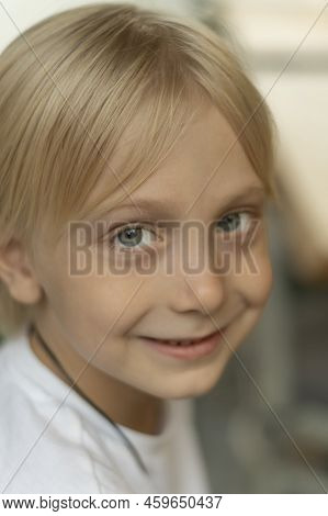 Close-up Portrait Of Blond Boy With Blue Eyes Looking Into The Camera. Fair-haired Child Smiling