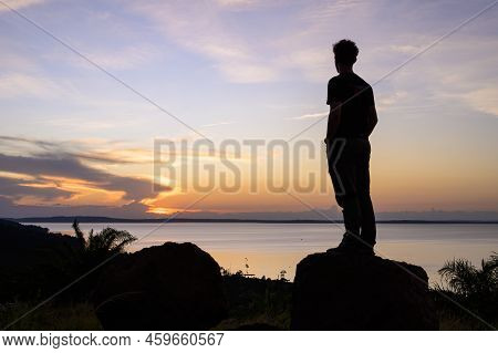 Kalangala, Uganda - May 10, 2022: Standing Boy Watching Colorful Sunset Near Kalangala (ssese Island