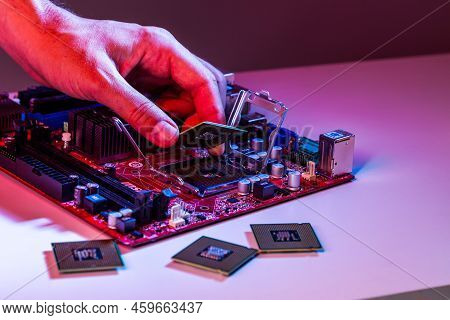 A Man's Hand Inserts A Processor Into The Motherboard Chipset.