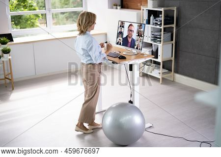 Woman Using Adjustable Height Standing Desk In Office For Good Posture