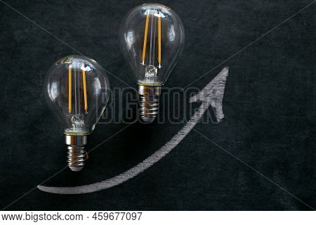 Rising Electricity Prices.light Bulb And Up Arrowon On A Black Chalk Board.electricity Cost.crisis O