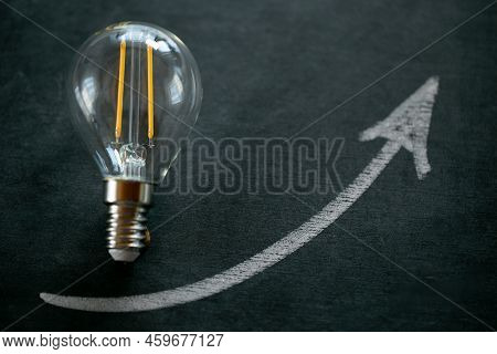 Electricity Prices.light Bulb And Up Arrowon On A Black Chalk Board.electricity Cost.crisis Of Energ