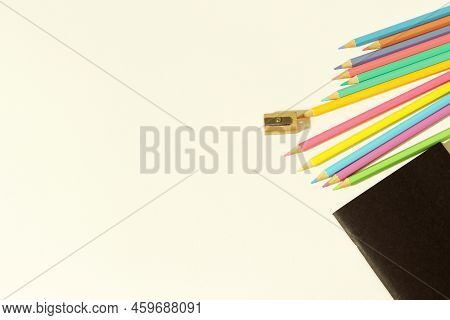 Color Pencil And Pencil Sharpener On Blank Notebook On White Background. Place For Your Text.